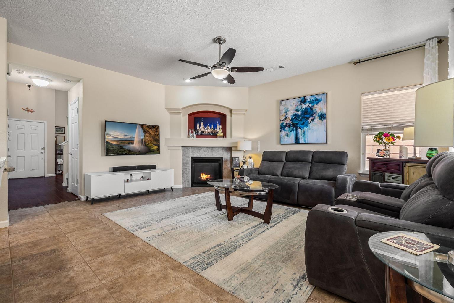 Spacious open-concept great room with high ceilings, corner gas fireplace, and natural light flowing into a kitchen with a center island.