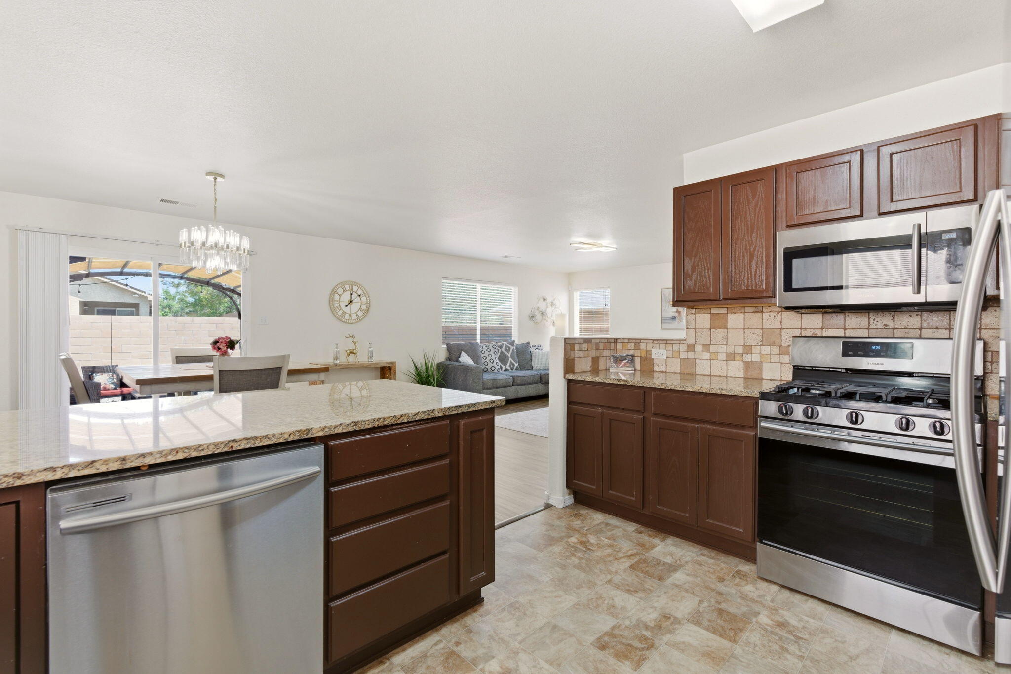 Kitchen at 7815 Latir Mesa Road NW in Albuquerque, showing granite countertops, stainless steel appliances, breakfast bar seating, and pantry-oriented storage.