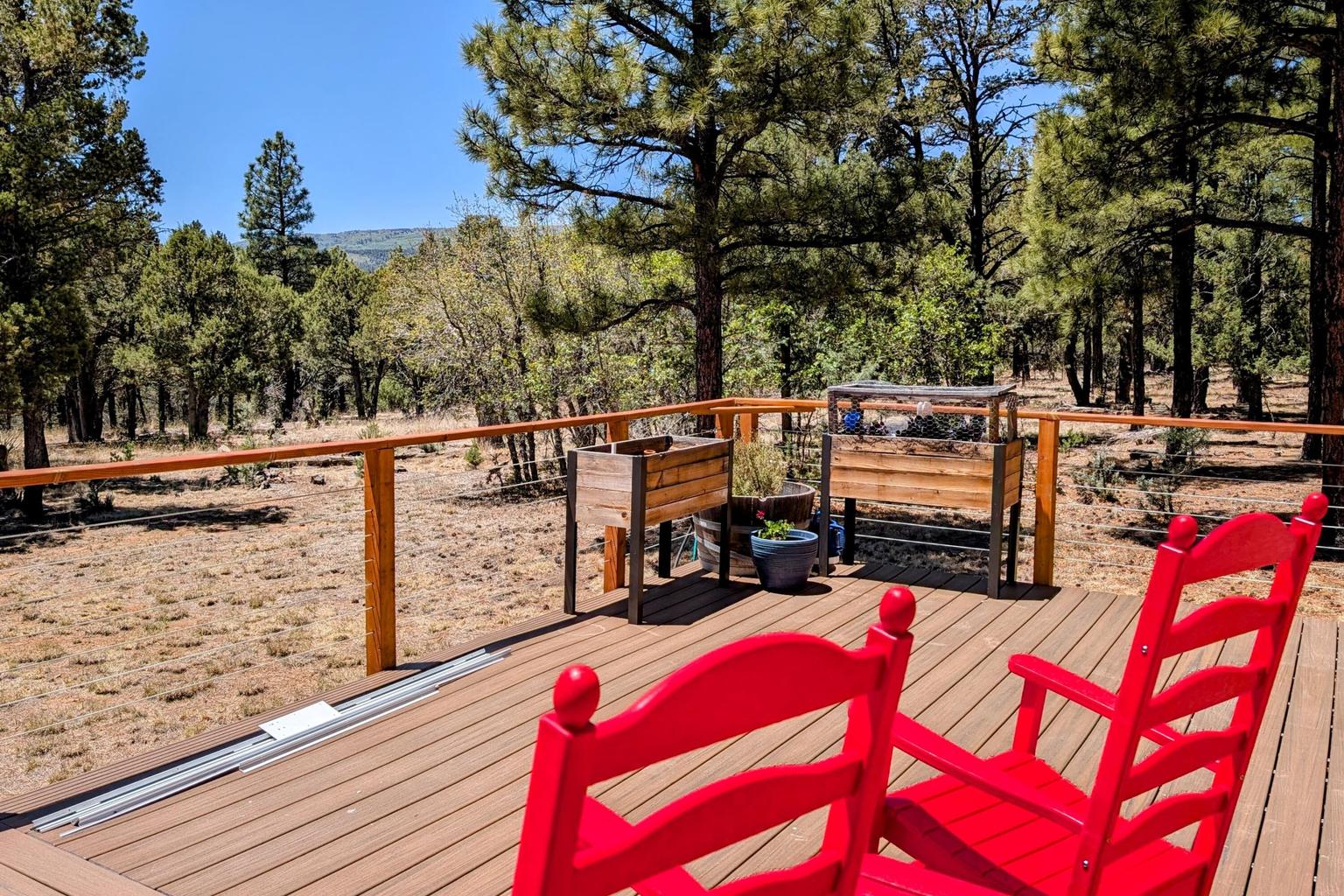 Trex deck outdoor living area at 459 4th Of July Road with mountain views, red chairs, and open-air relaxation space.