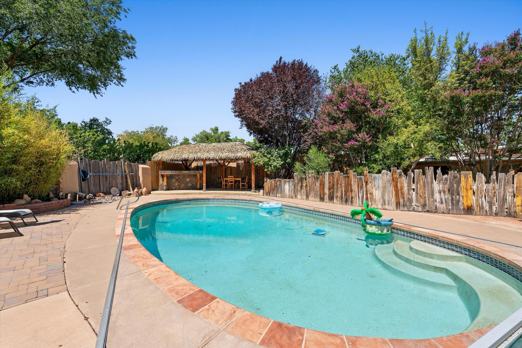 Private curved in-ground swimming pool with mature landscaping and outdoor seating at 4068 Dietz Farm Circle NW.