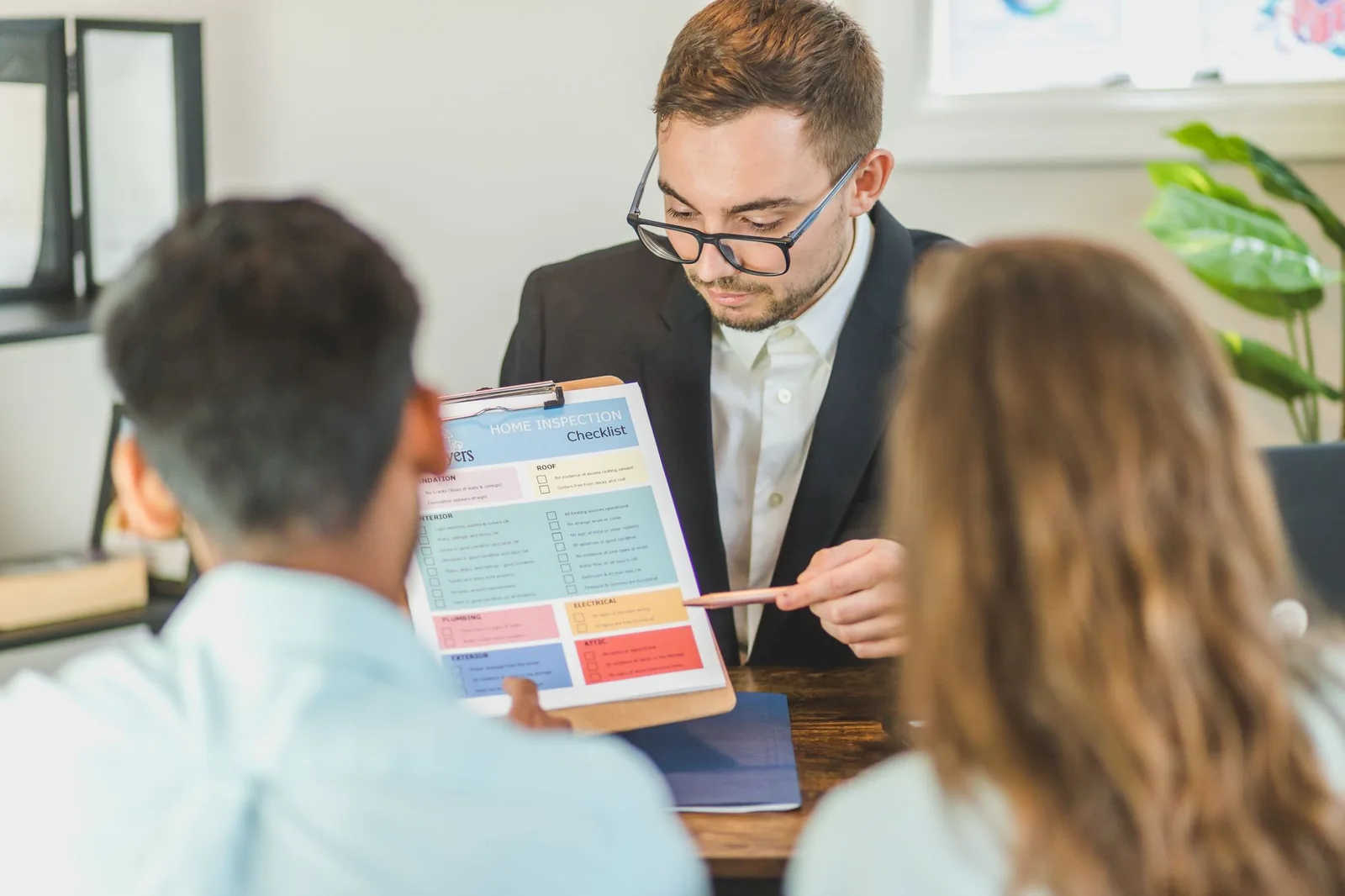 A real estate professional reviewing a home inspection checklist with two clients.