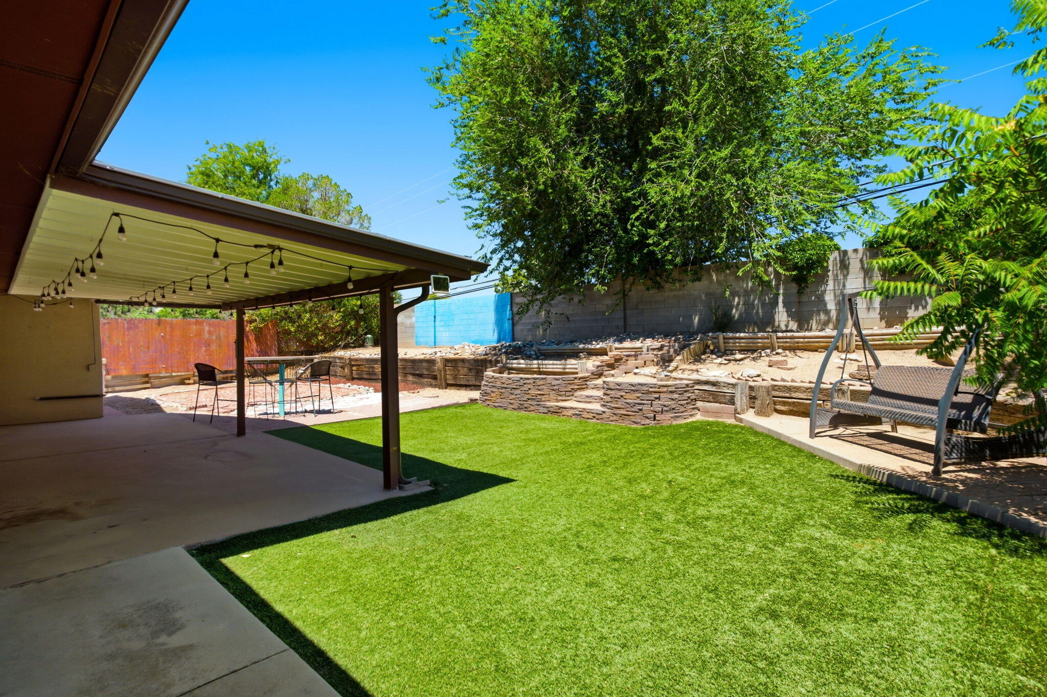 Covered backyard patio opening to a walled low-maintenance yard