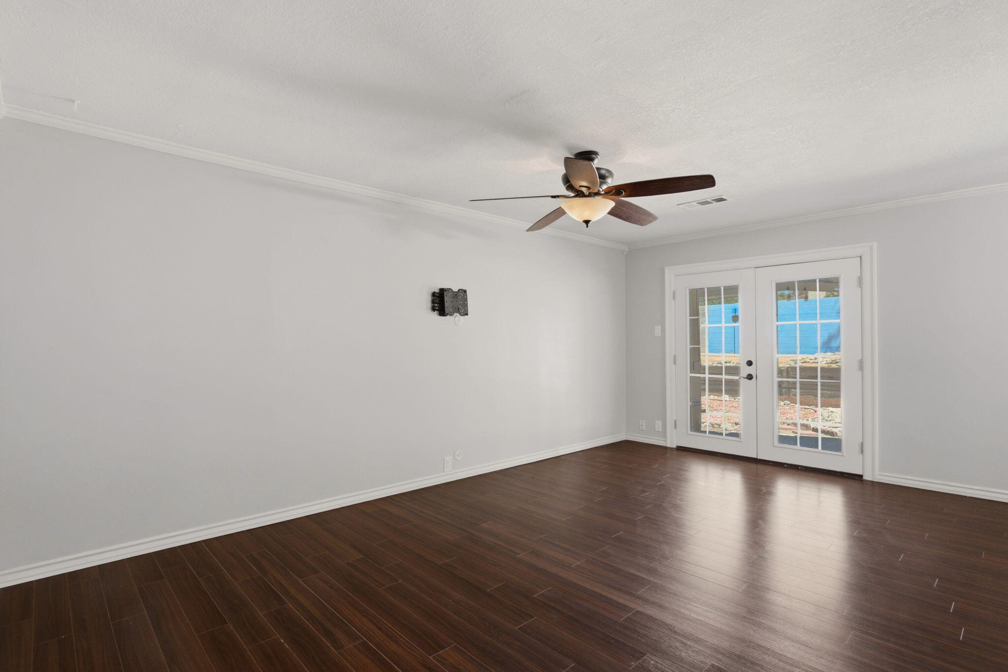 Second living area with dark wood flooring and French doors to the patio
