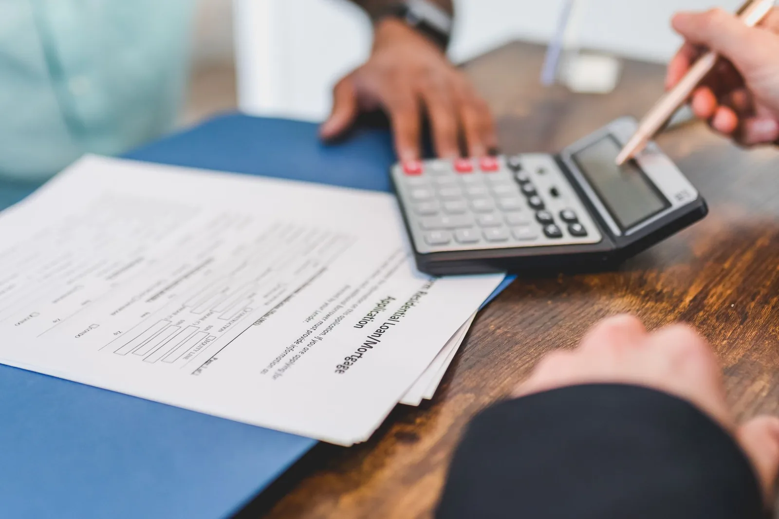 Hands reviewing real estate financing documents with a calculator.