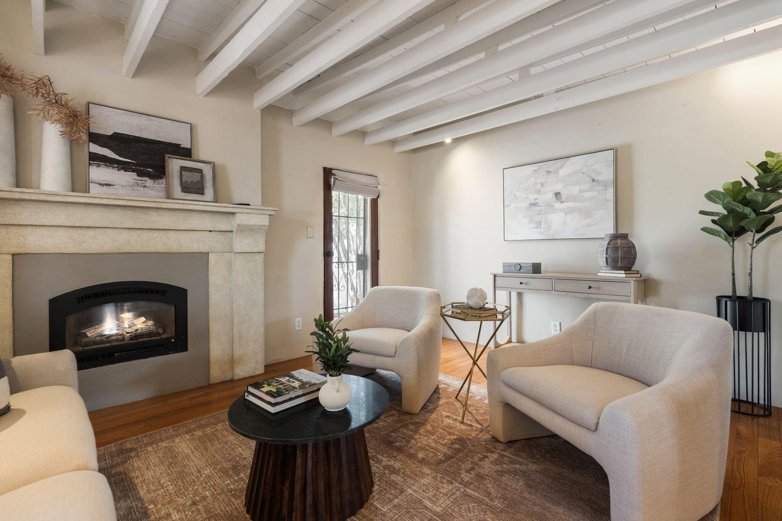 Living room at 1023 11th Street SW with exposed beams, wood floors, a gas-log fireplace, and an arched opening