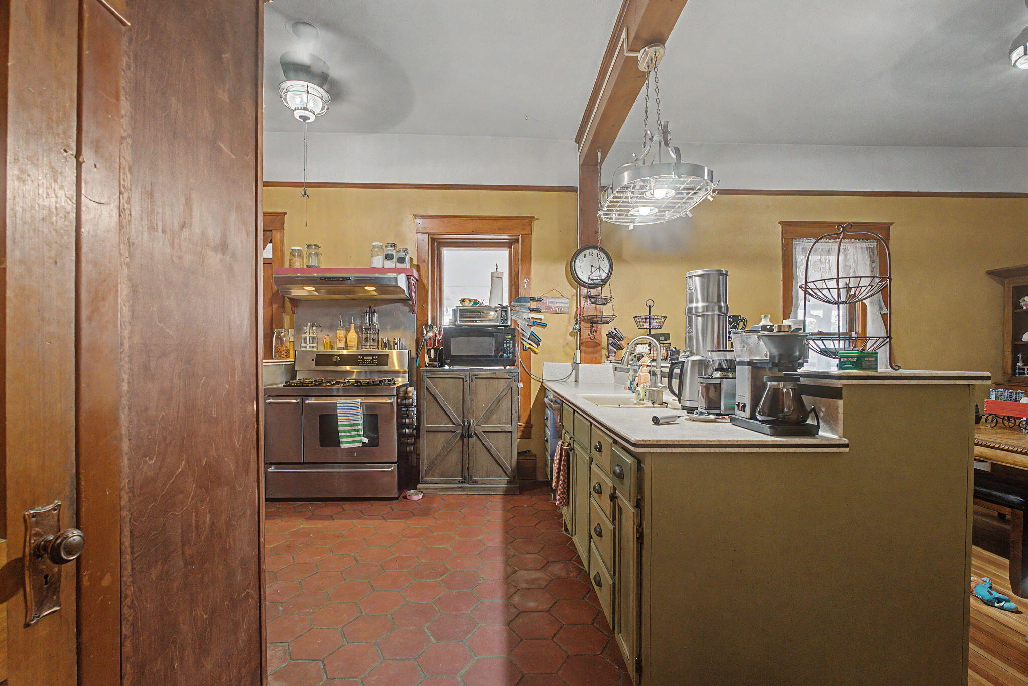 Main kitchen with central work island, wood trim, and red tile flooring