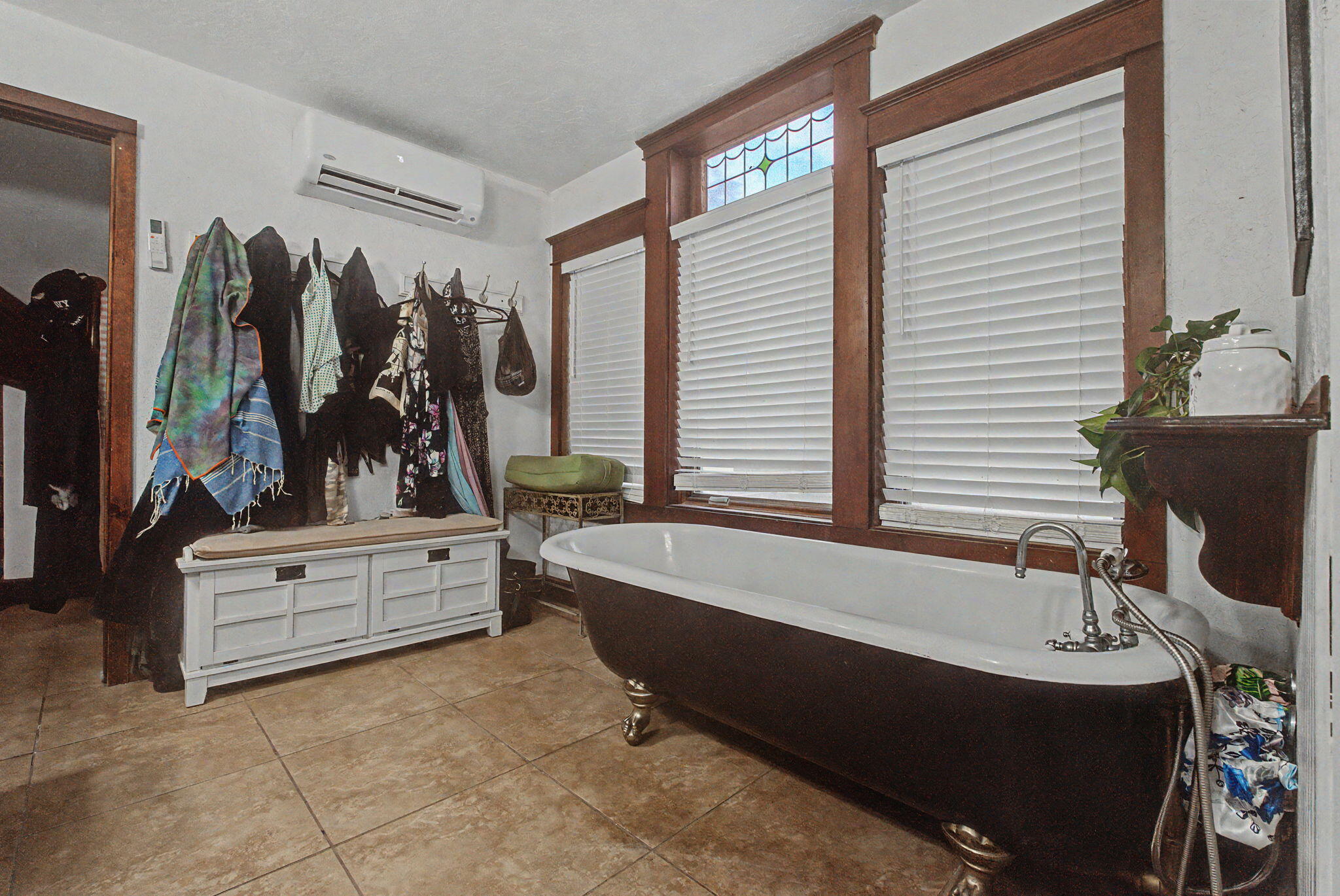 Bathroom with a clawfoot tub beneath tall wood-trimmed windows