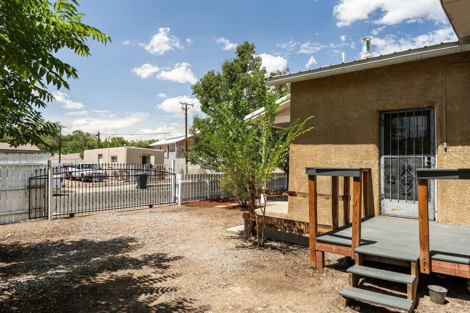 Gated side yard at 1023 11th Street SW in Albuquerque with fencing and a narrow outdoor passage beside the stucco home