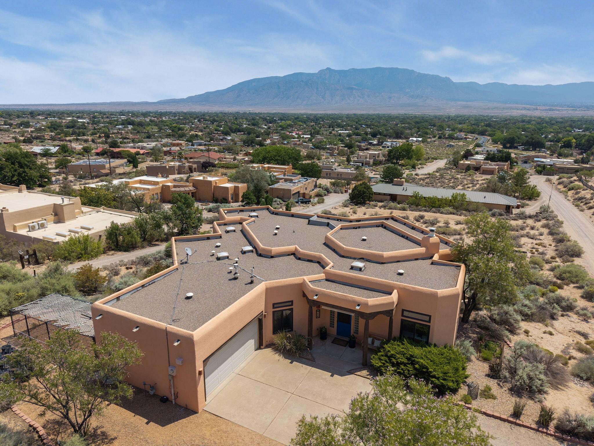 Aerial view of 40 Sereno Road in Corrales with the Pueblo-style roofline and Sandia Mountains in the distance