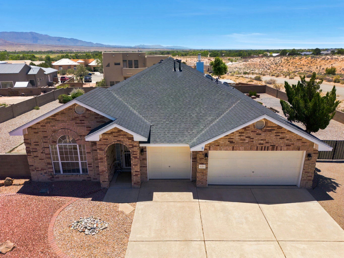 Aerial view of the brick-front single-story home at 1684 Savannah Court NE, showing the three-car garage and xeriscaped front yard.