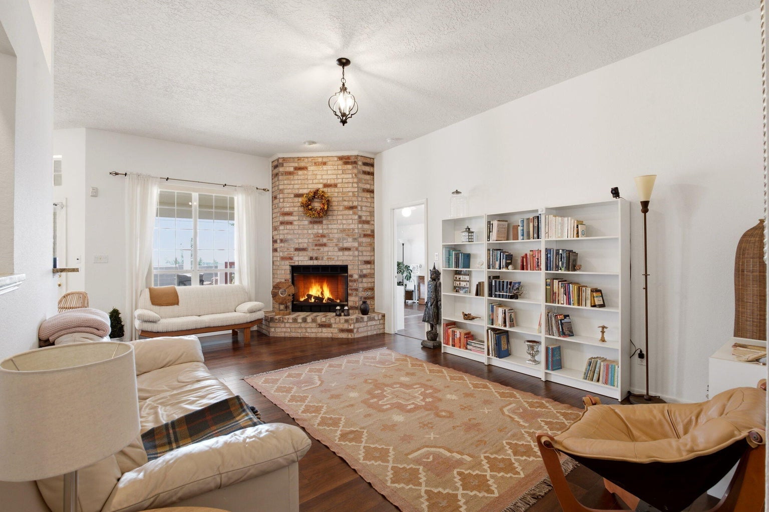Second living area at 1684 Savannah Court NE with wood flooring, white built-in bookcases, and a brick gas-log fireplace.