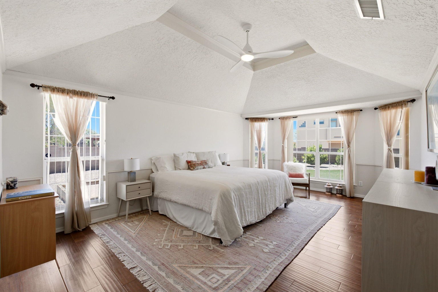 Primary suite at 1684 Savannah Court NE with wood flooring, a tray ceiling, multiple windows, and a glass door to the exterior.