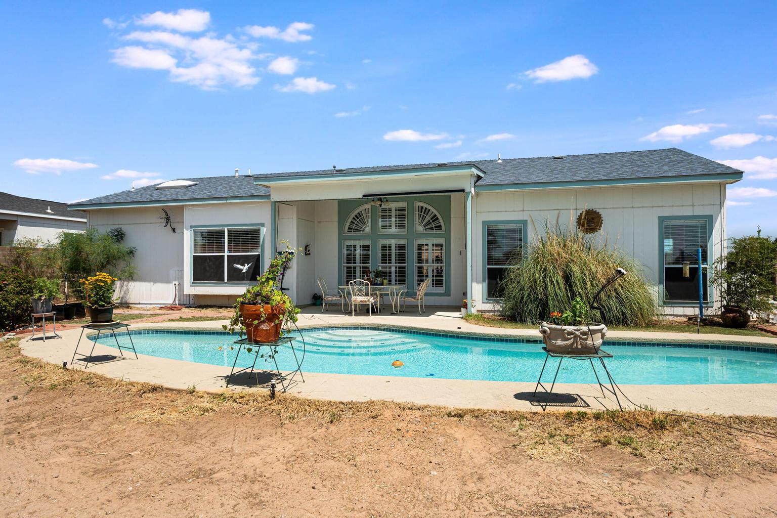 Private in-ground pool behind 7250 Pelona Court NE with a rear patio and the single-level home beyond