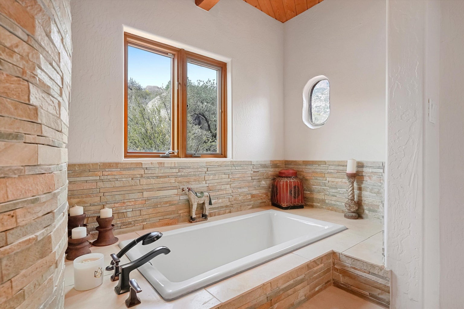 Primary bathroom soaking tub beneath a bright window