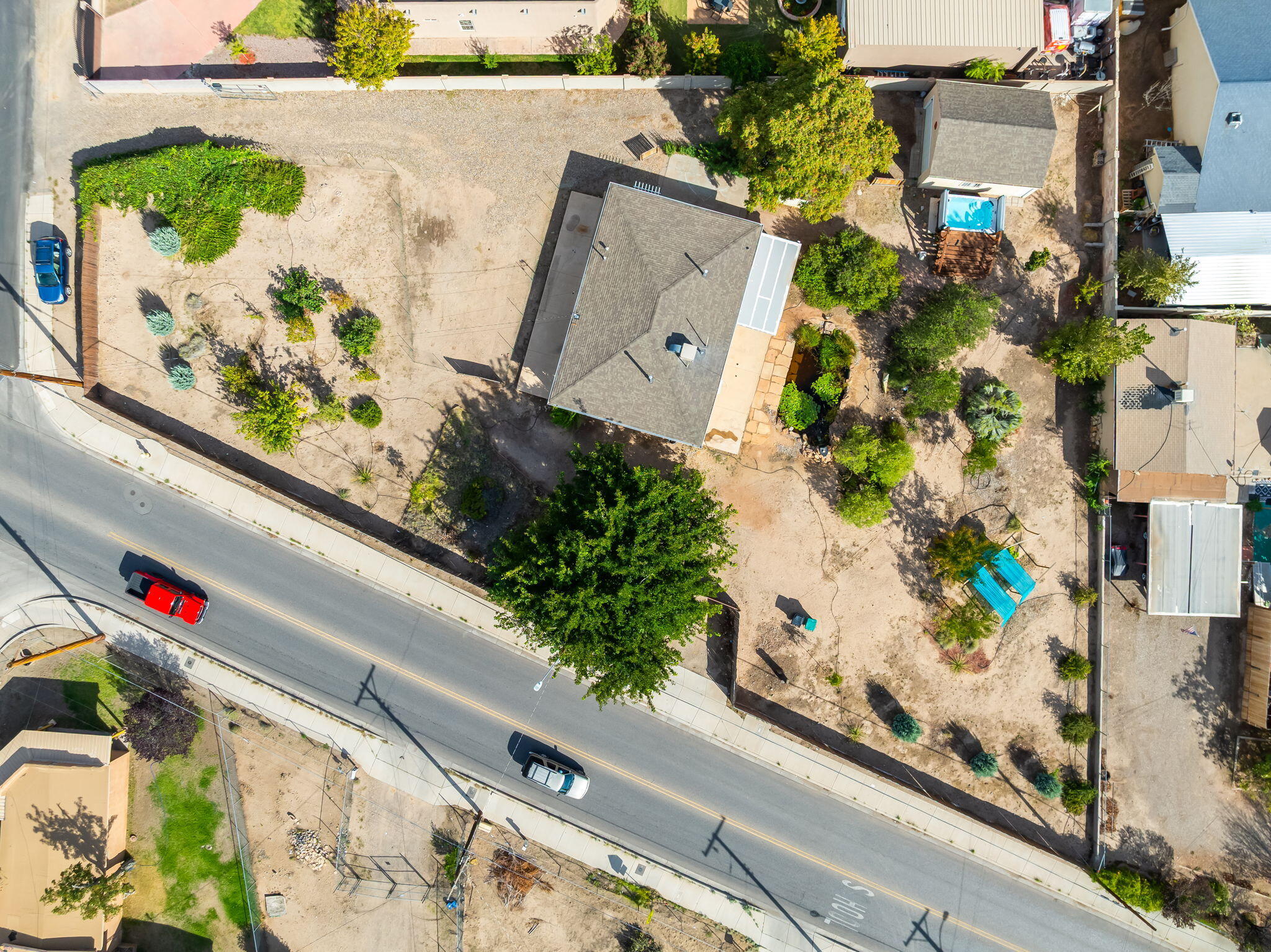 Aerial view of 406 Atrisco Drive SW showing the home, broad gated parcel, mature trees, garden areas, and separate garage
