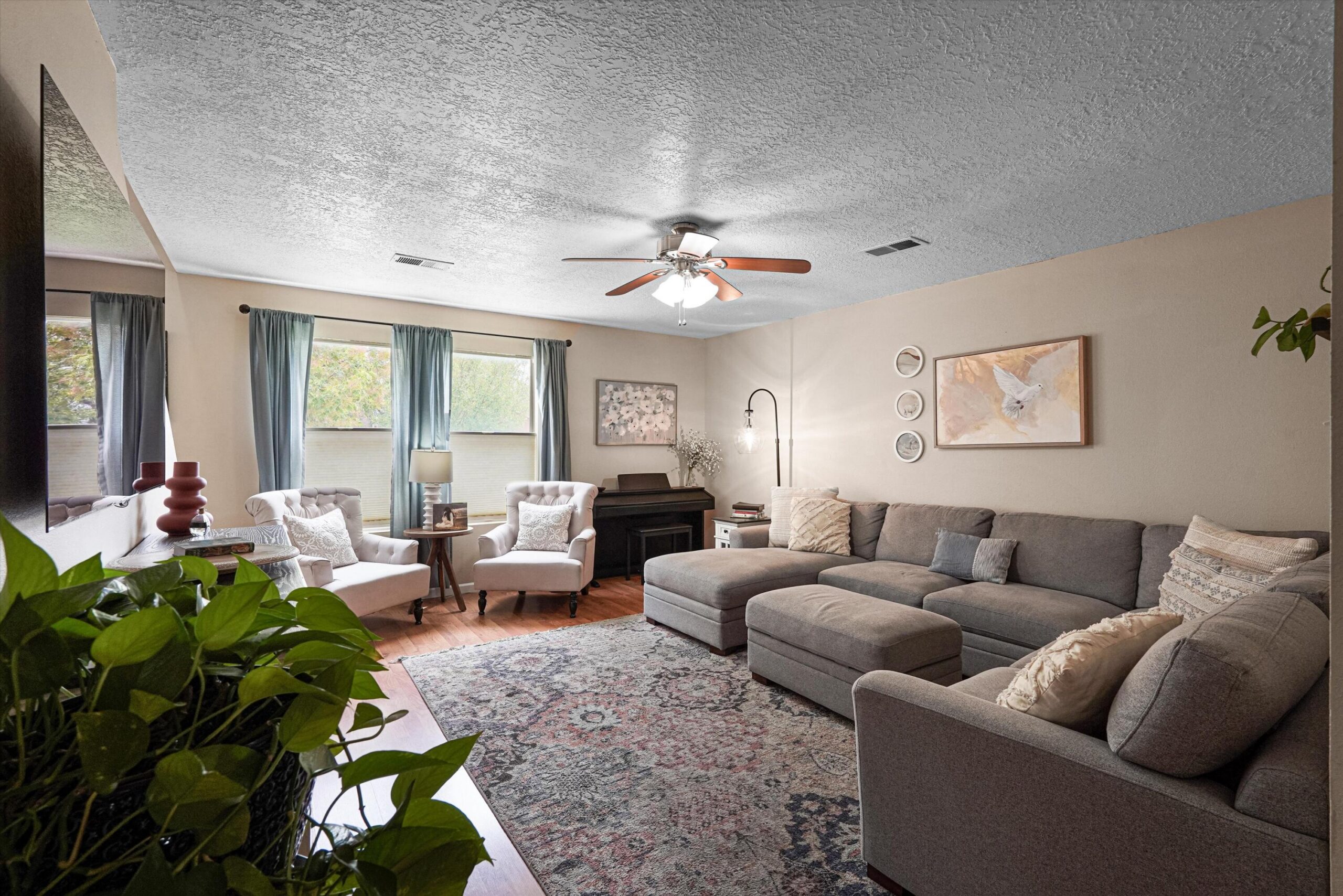 Living room with sectional seating, armchairs, piano, and natural light