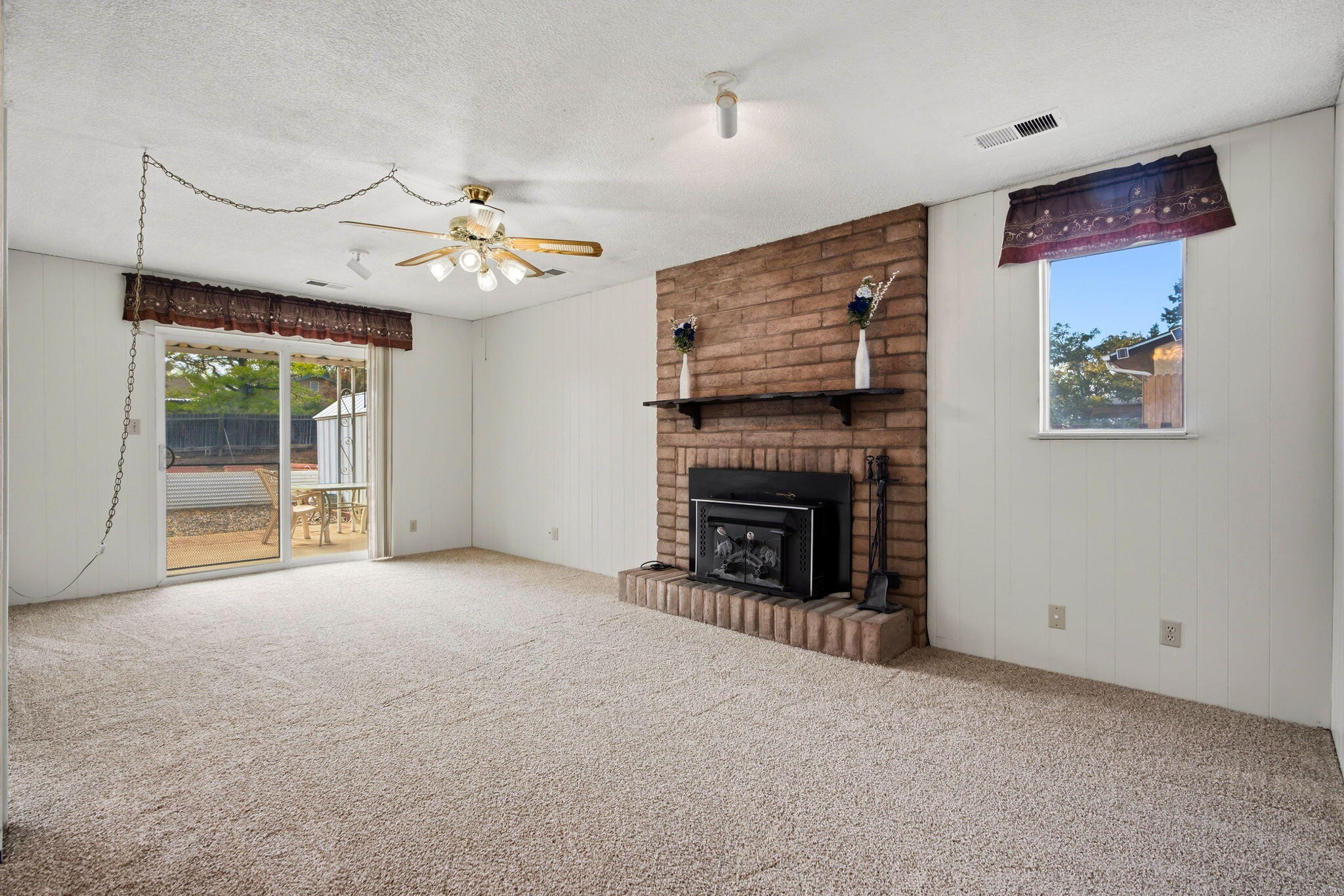 Living room with a brick wood-burning fireplace and sliding patio door at 4108 Leon Grande Avenue SE