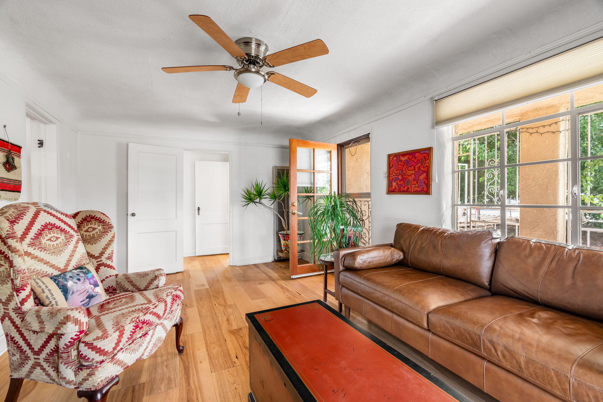 Living room at 406 Atrisco Drive SW with hardwood floors, large windows, ceiling fan, and an open doorway to the dining area