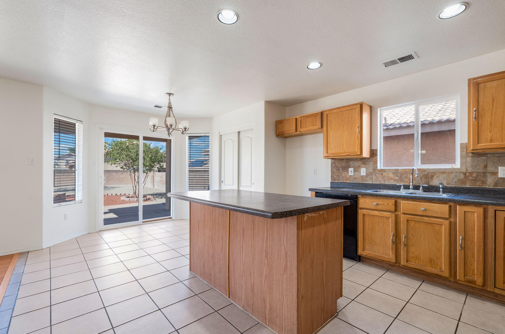 Kitchen island, wood cabinetry, tile backsplash, and adjacent breakfast nook.