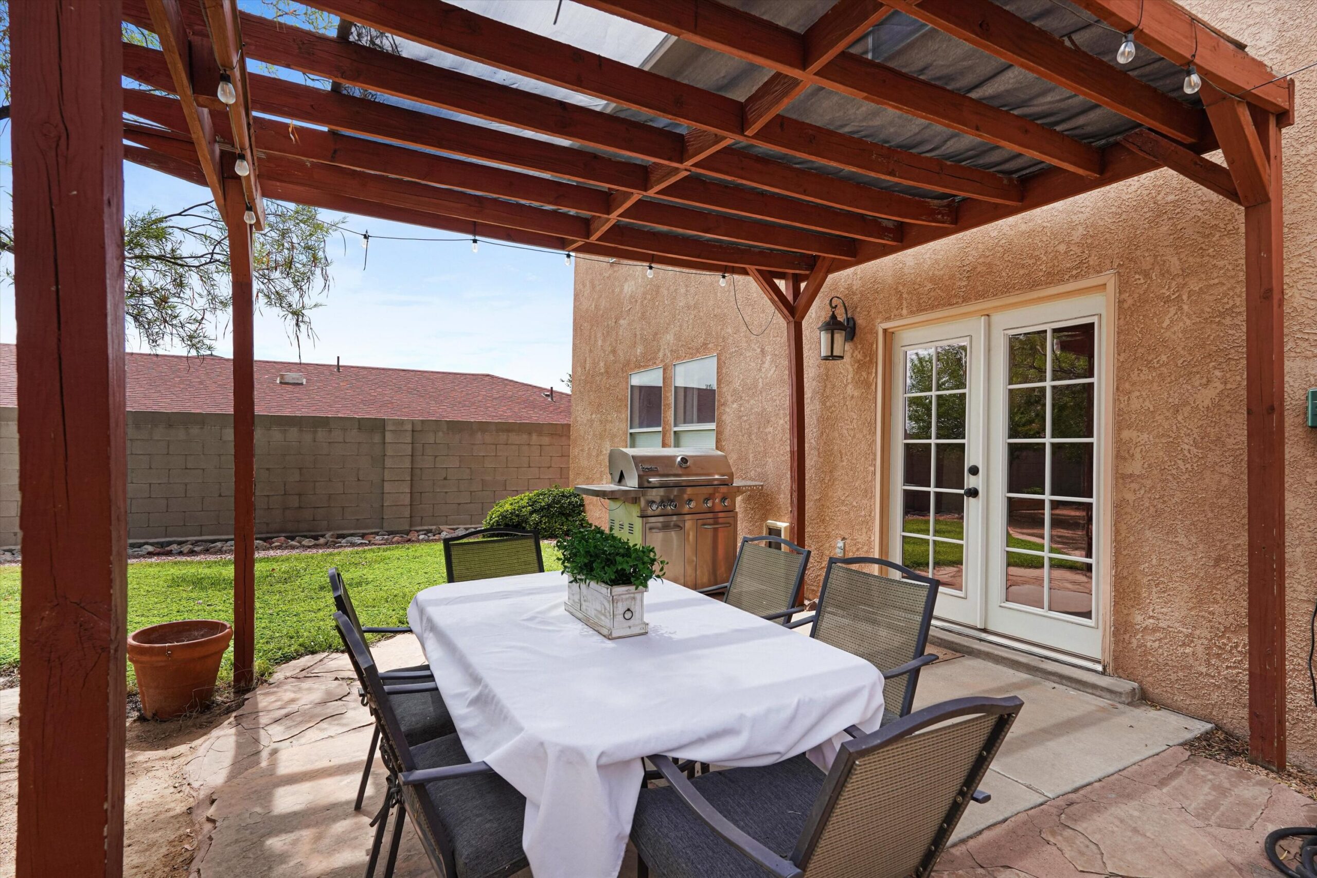 Covered backyard patio with outdoor dining table and French doors