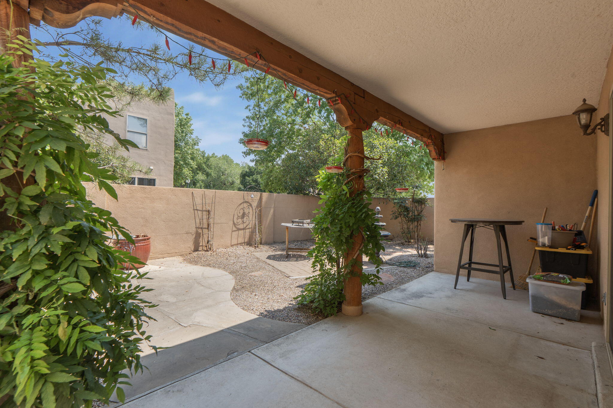 Covered back patio with exposed wood beams and landscaped yard at 3601 Calle Oveja Court NW