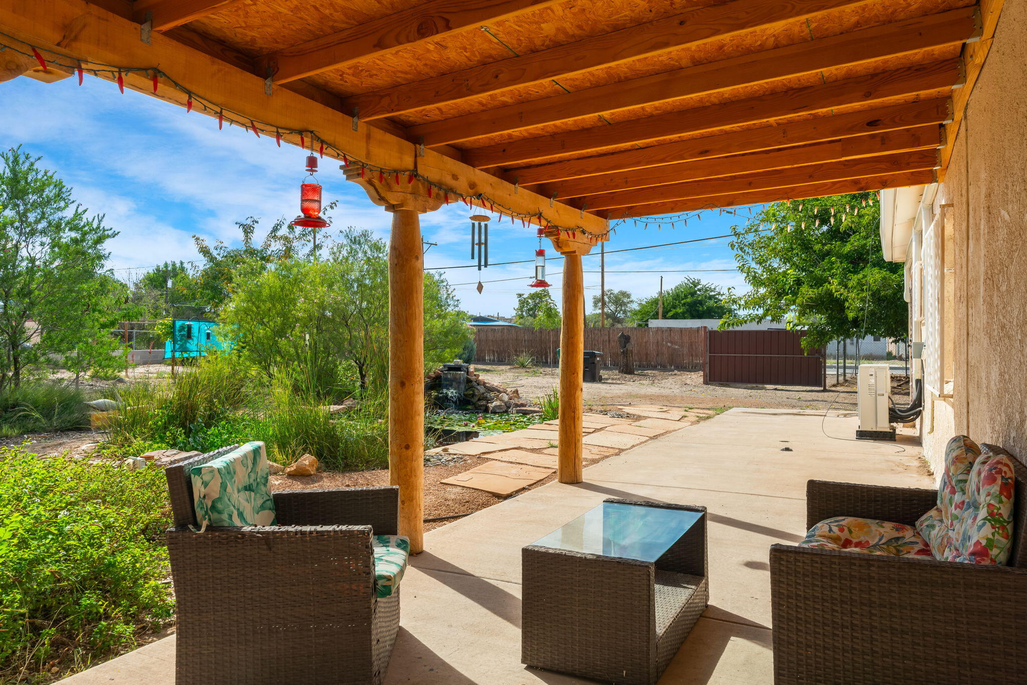 Covered patio at 406 Atrisco Drive SW overlooking mature landscaping and open yard areas