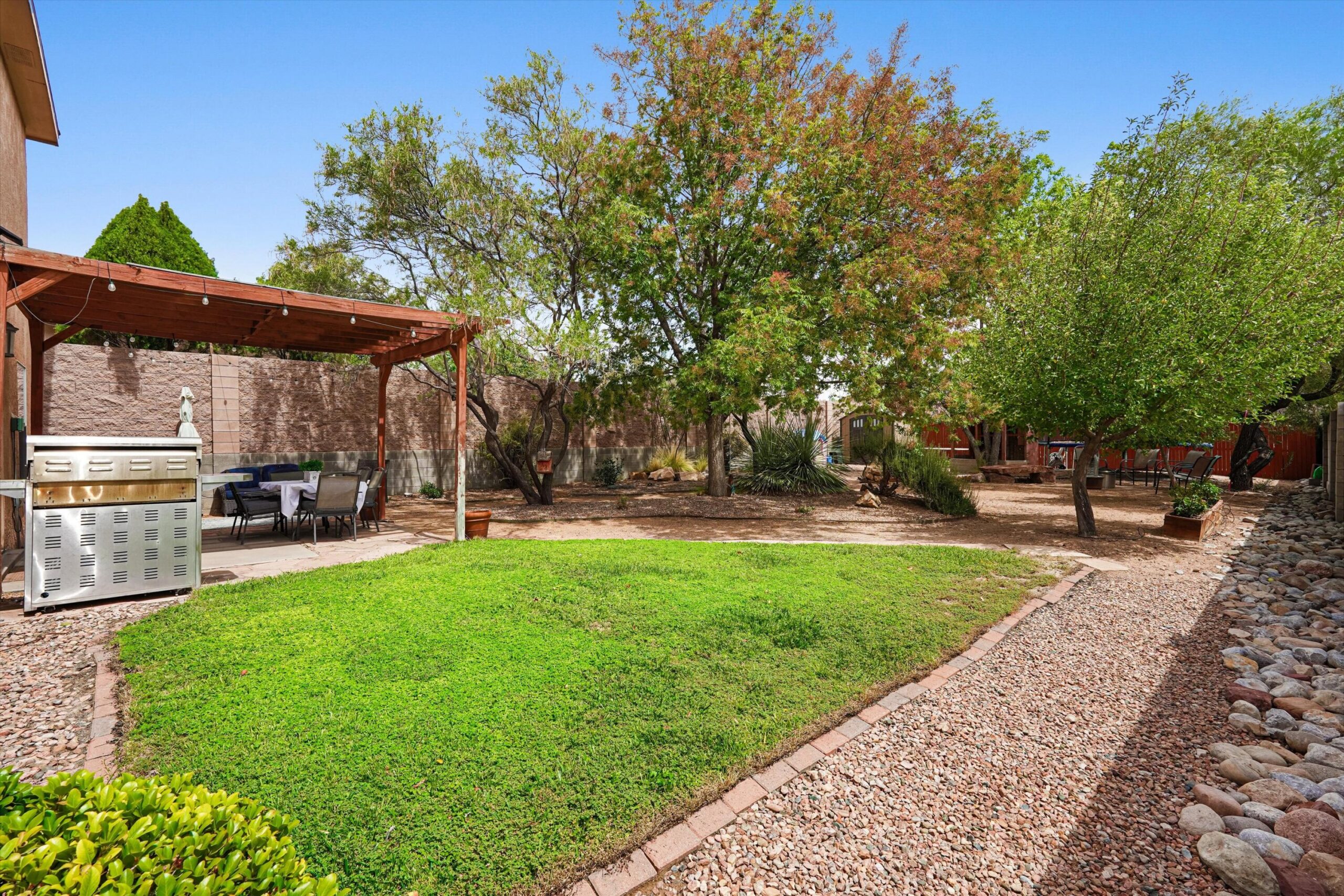 Landscaped fenced backyard with green lawn and mature trees