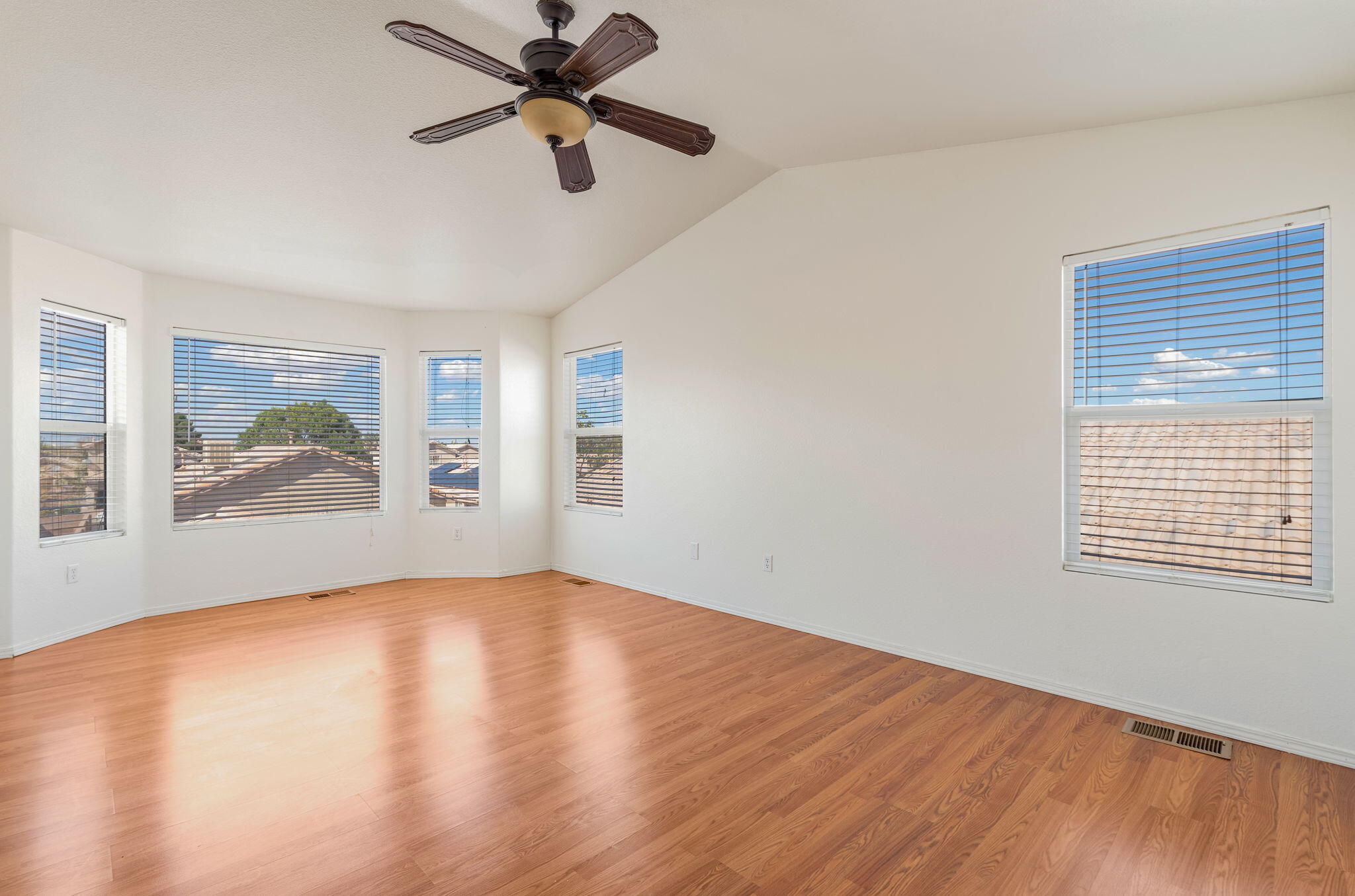 Primary suite with a bay window, high ceiling, and ceiling fan.