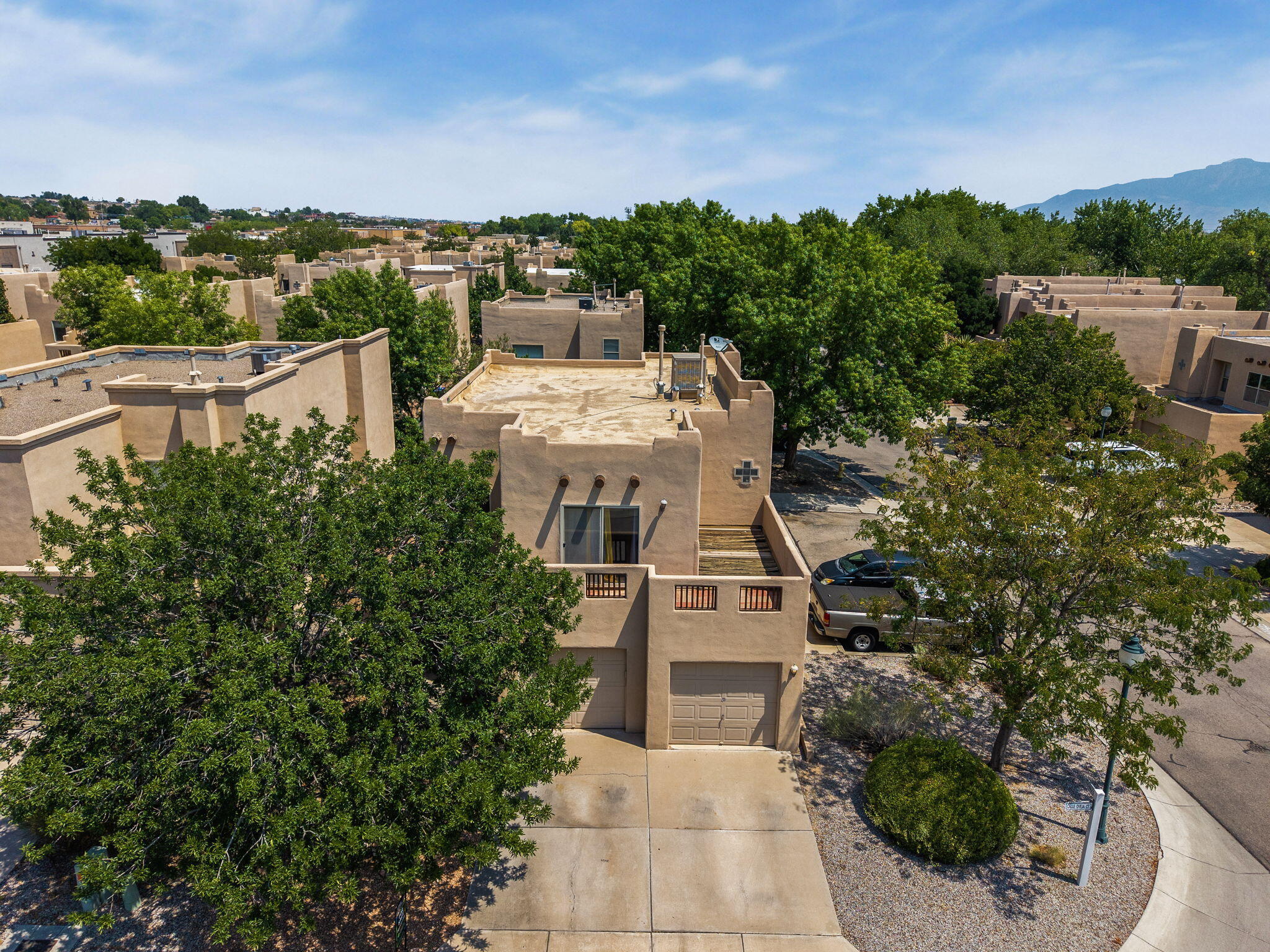Aerial view of the Pueblo-style home and tree-filled setting around 3601 Calle Oveja Court NW