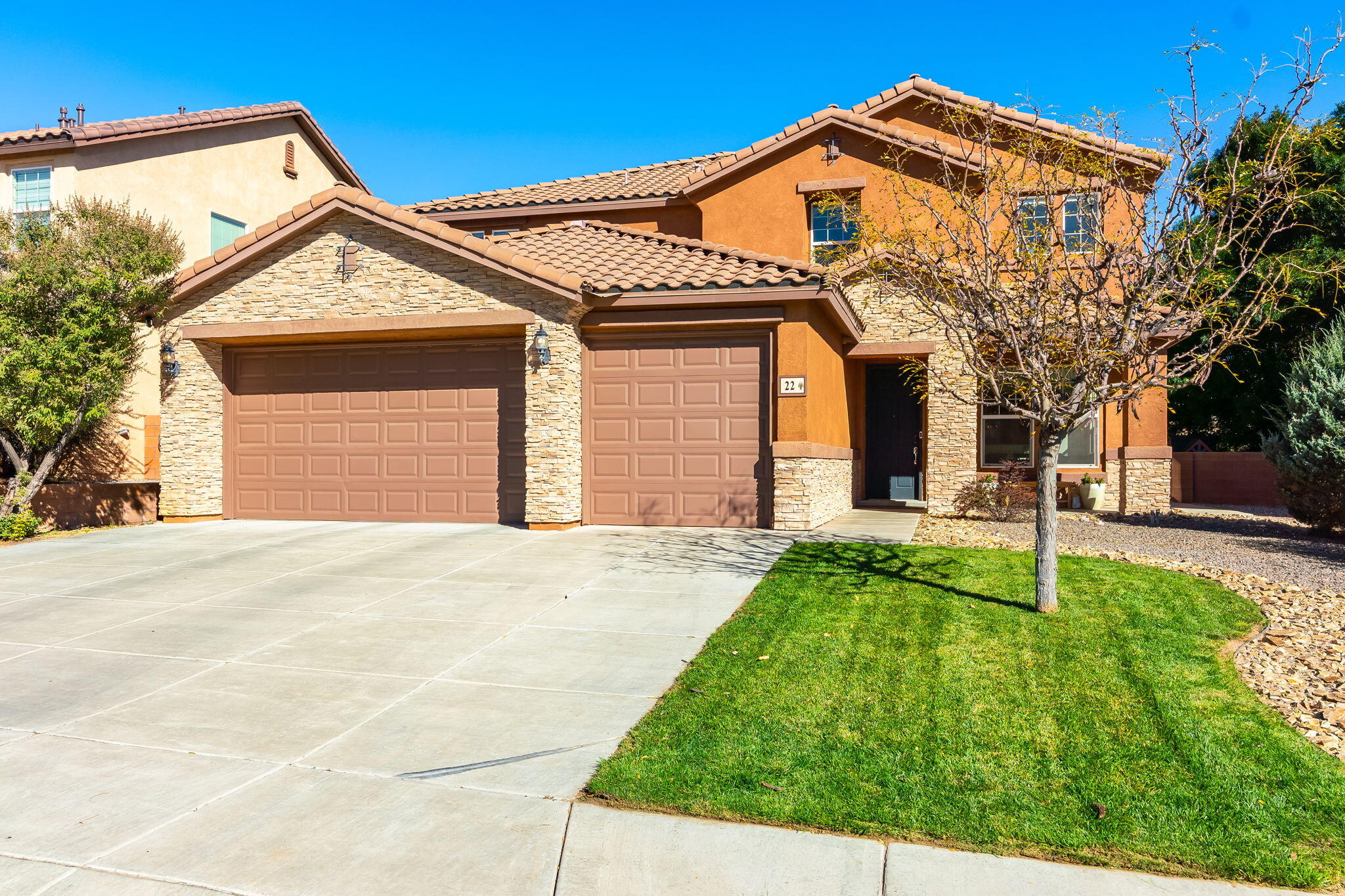Front exterior of 22 Monte Vista Drive NE in Rio Rancho with a tile roof, stone accents, and three-car garage