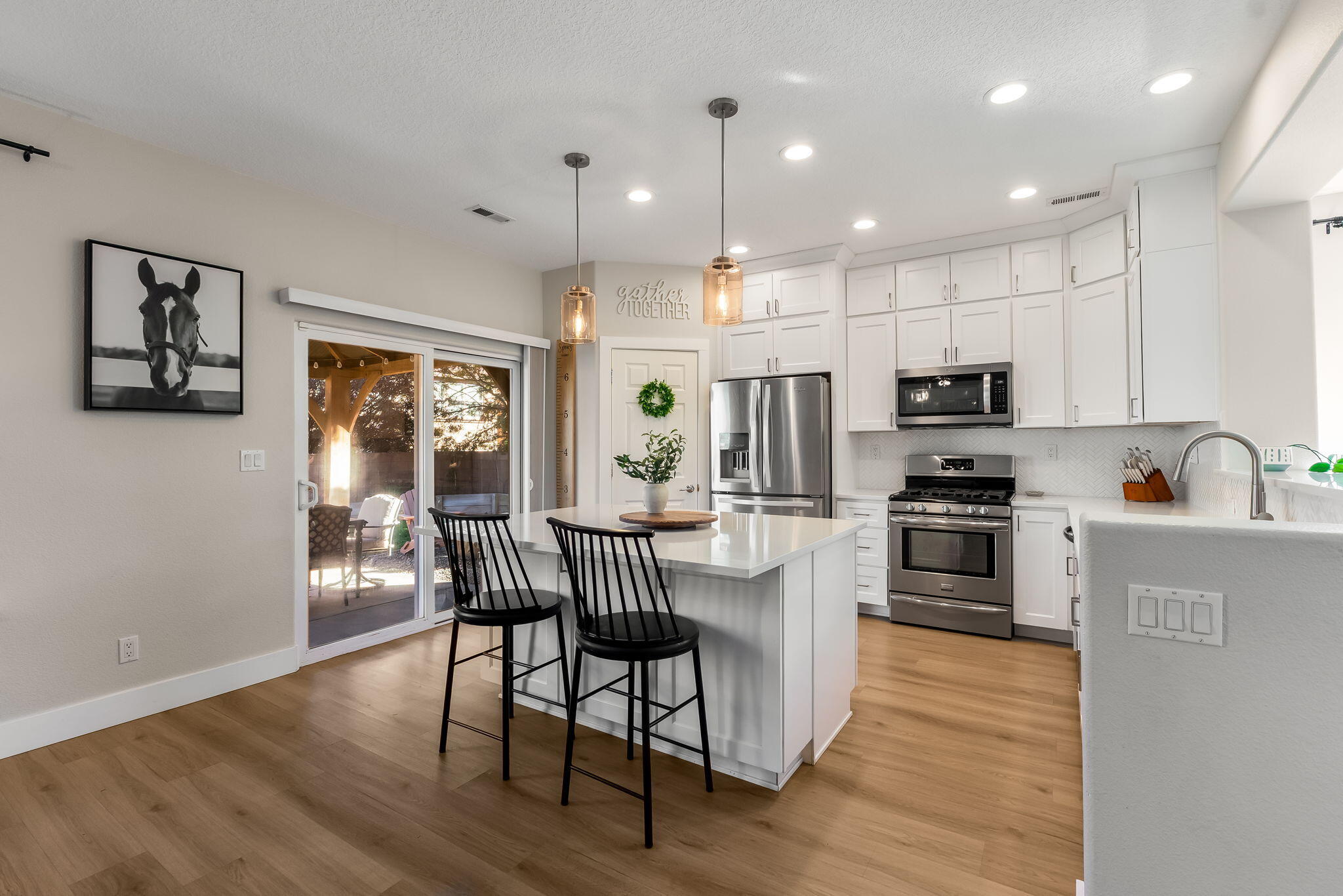 White kitchen cabinetry, quartz island, stainless appliances, and sliding patio door at 22 Monte Vista Drive NE